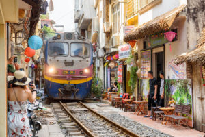 Best things to do in Hanoi, Vietnam - Train passing by in Train Street with a lady photographing it on her mobile