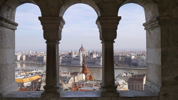 Hungarian parliament through a historic window in Budapest