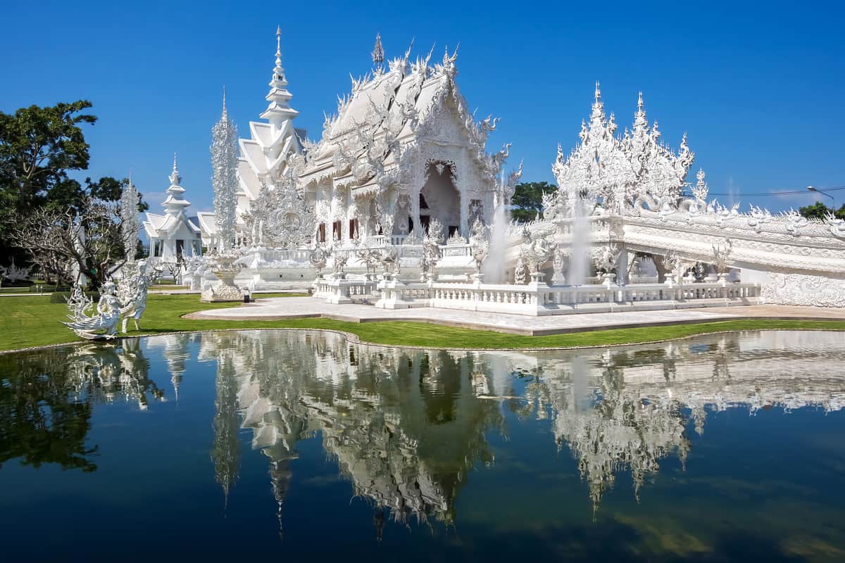 White temple in Chiang Rai reflecting in water.