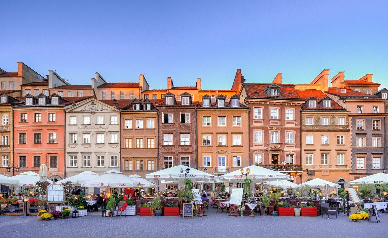 Brown and beige buildings on a big square with lots of restaurants in Warsaw, Poland