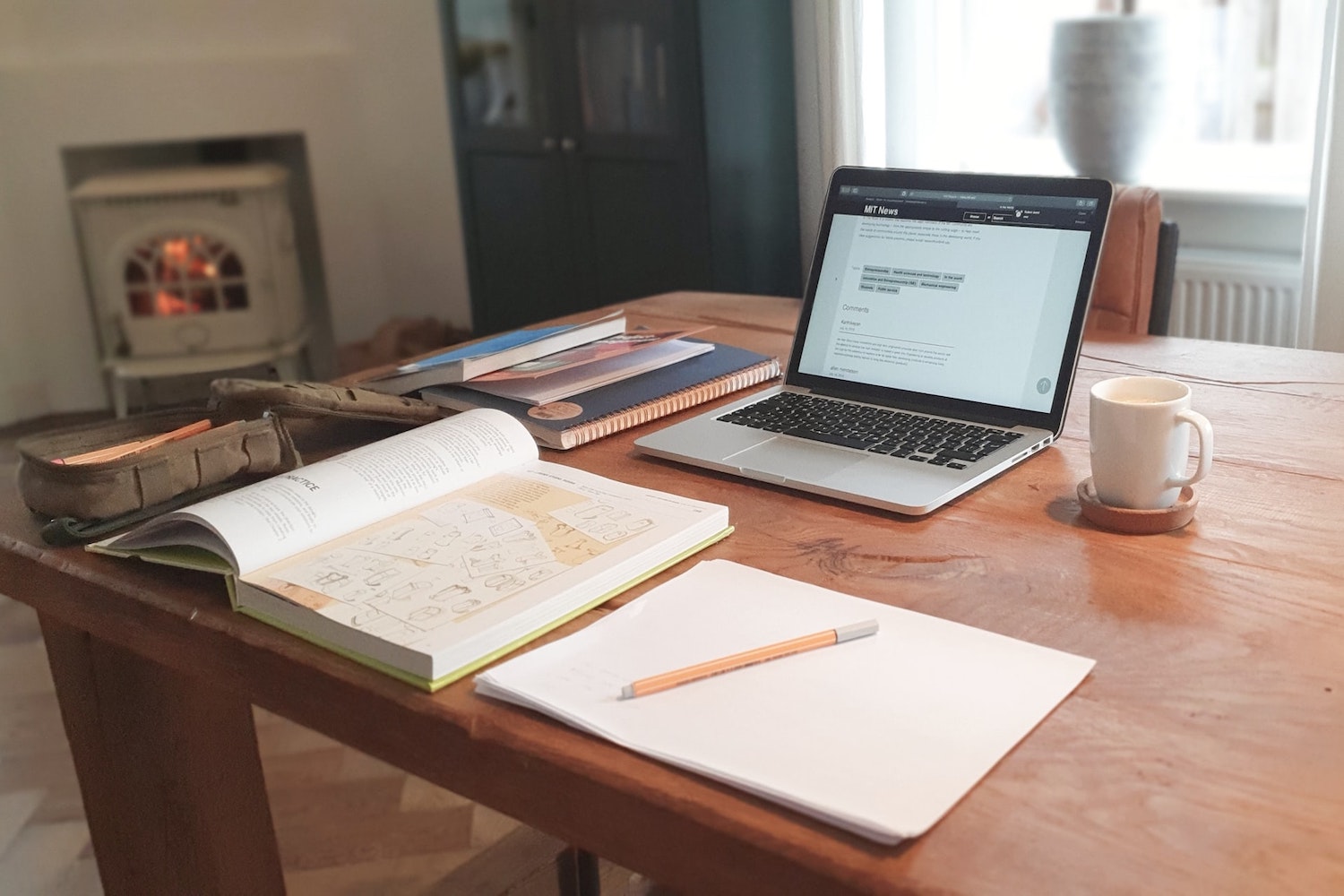 Laptop on a desk with a notebook and a pen