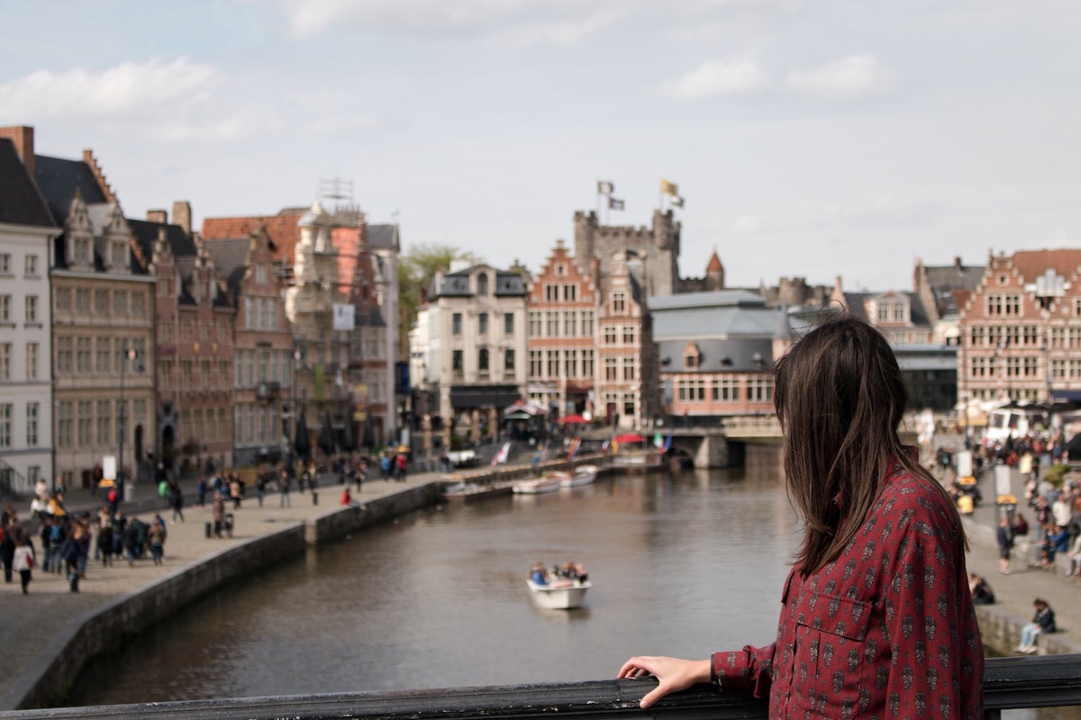 Woman posing on a bridge above the canal in Belgium and with Belgian buildings in the background