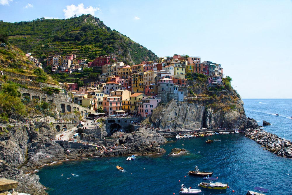 view of Riomaggiore with colorful houses on the elevated rock and the sea in the background