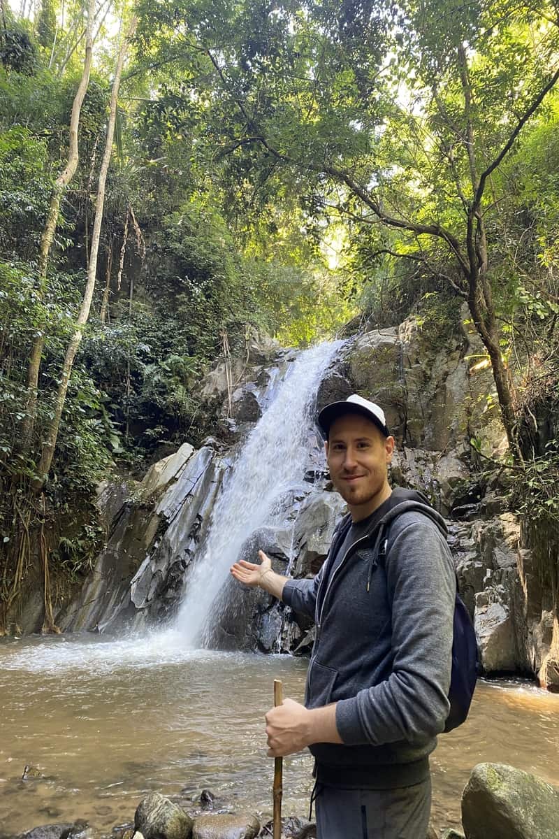 Man by a waterfall in a forest.