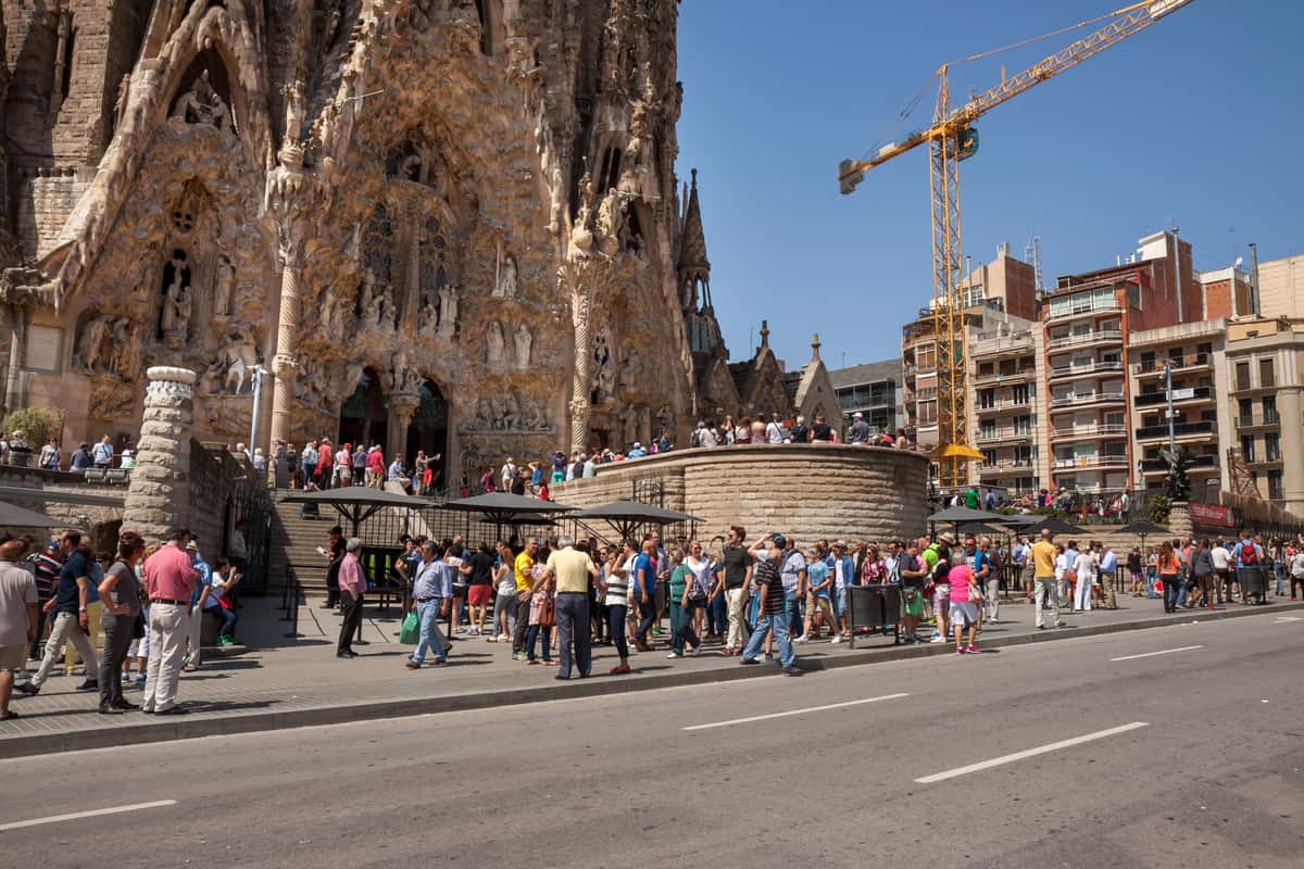 People walking near a grand cathedral. Tour de la Sagrada Familia