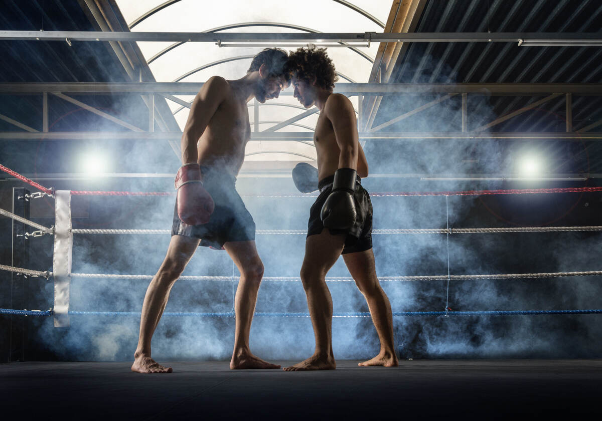 Two men kickboxing in a gym.