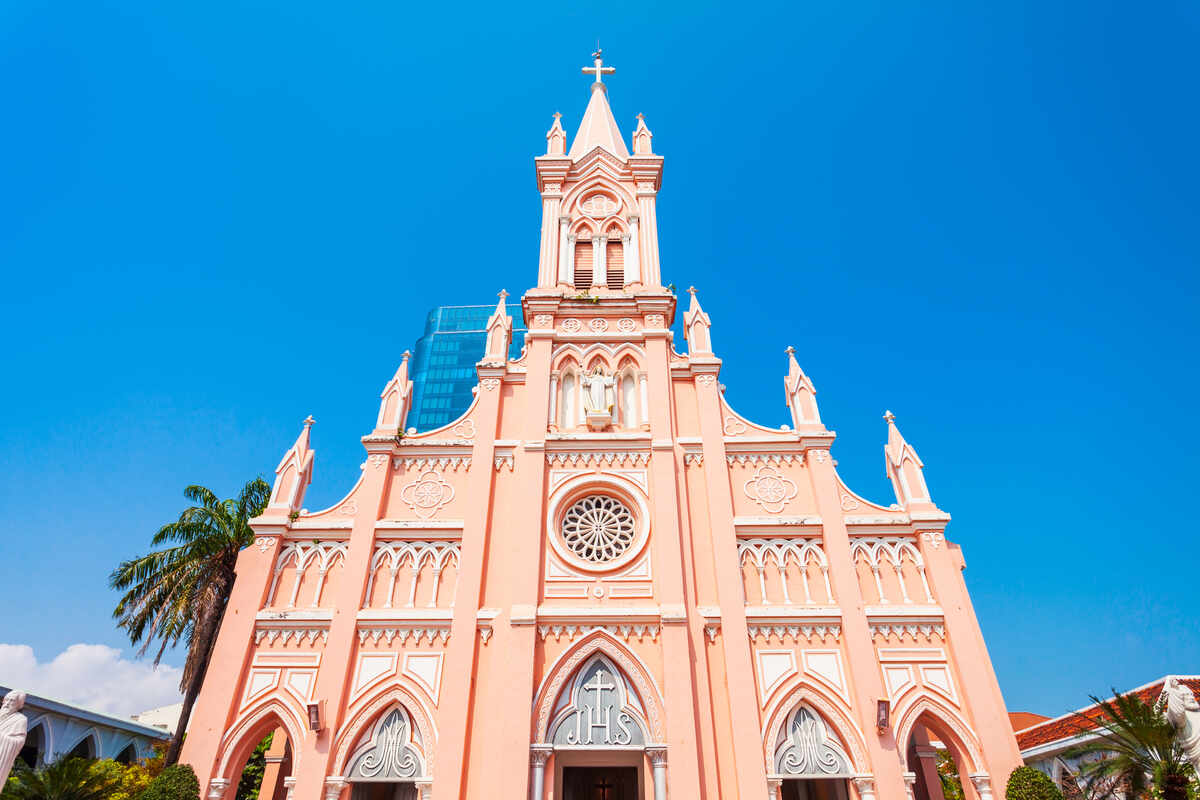Pink church tower against a blue sky. See Da Nang Cathedral the pink church