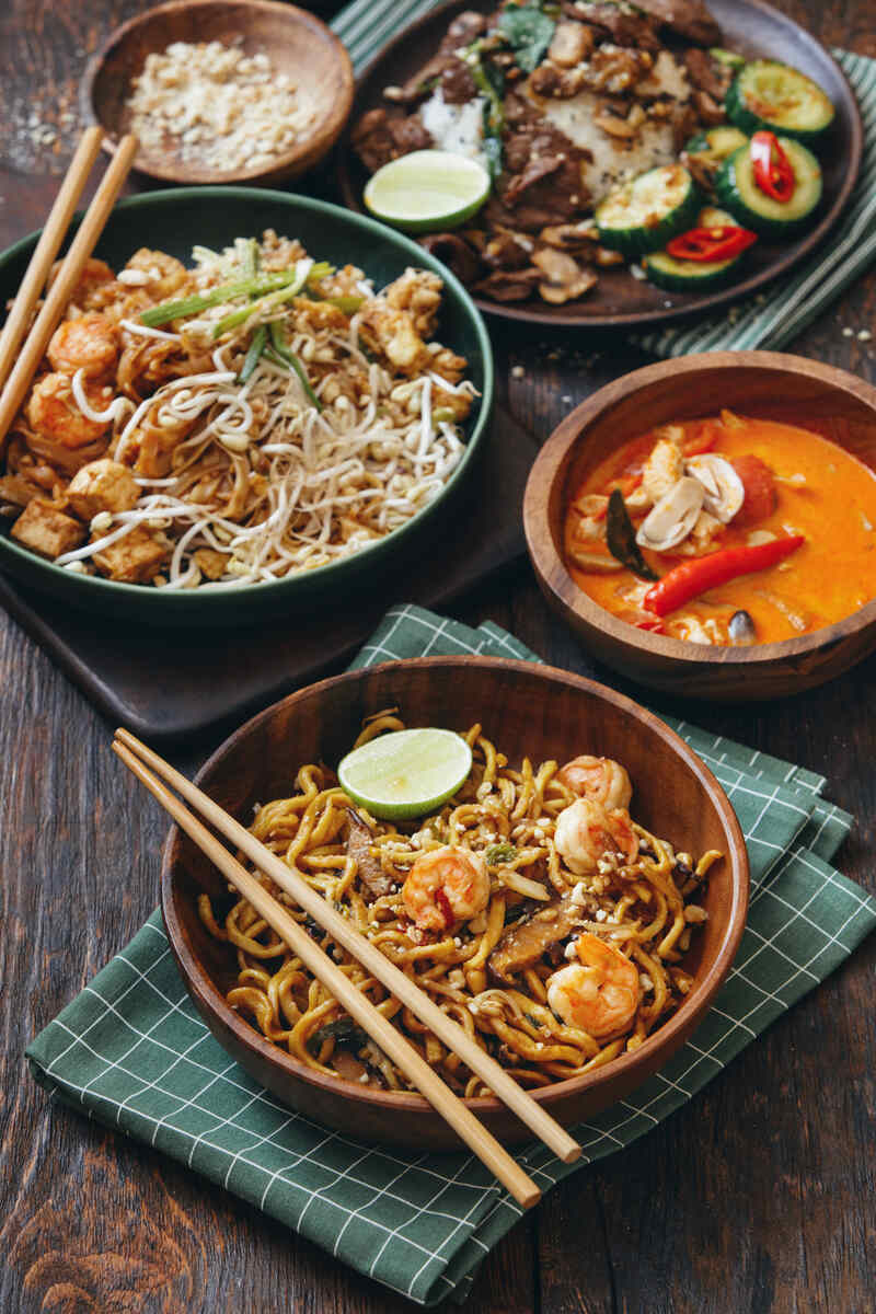 several Thai dishes in bowls with chopsticks