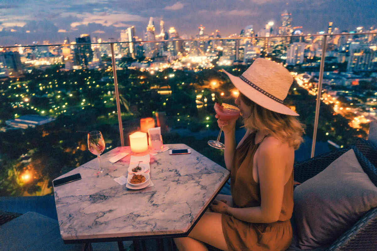 Woman sipping on a drink at a rooftop bar in Bangkok