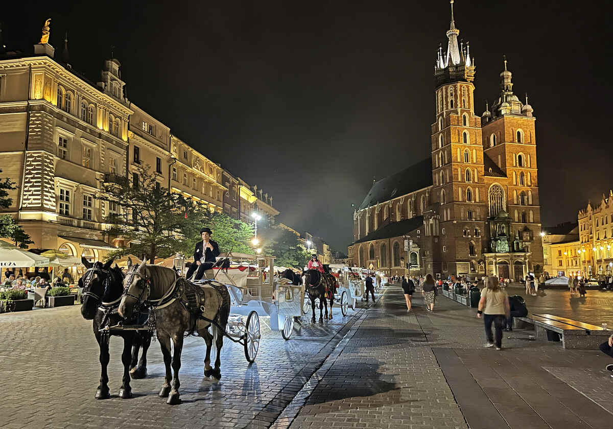 Horse-drawn carriages in city square at night. Things to do in Krakow at night