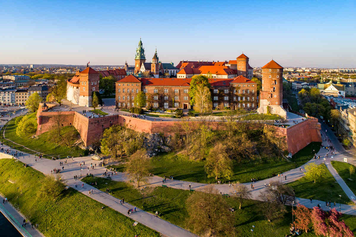 Wawel-Castle-in-Krakow - Castle on a hill with city below at dusk.