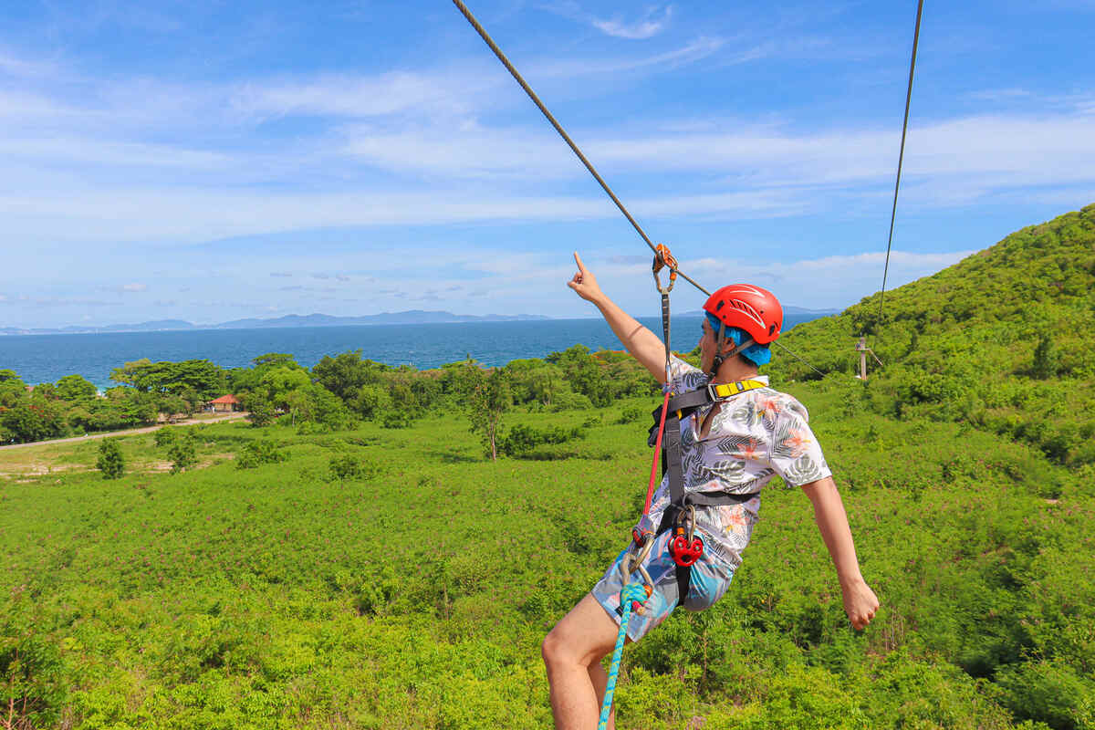 Man going down on zipline with the sea in the background