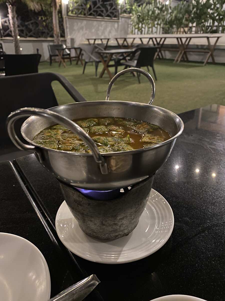 Hot soup served in a metal pot on a table.