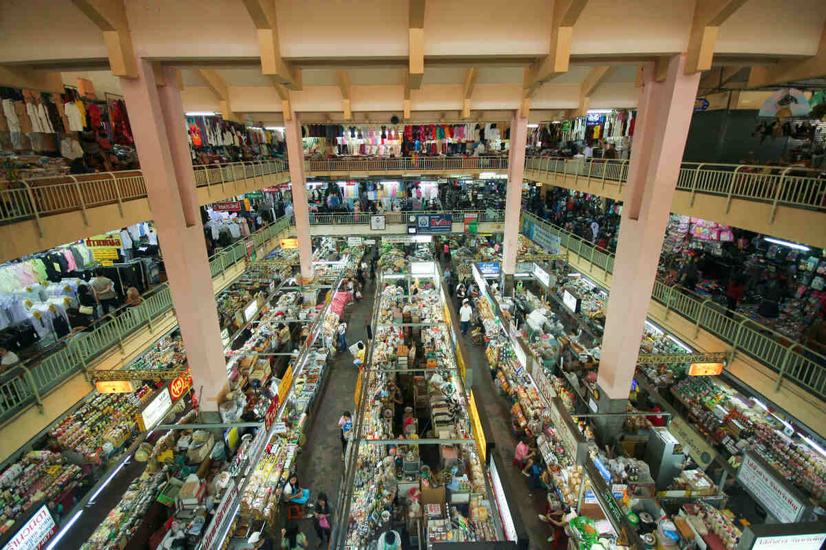 An interior view of a bustling market with rows of merchandise and shoppers.