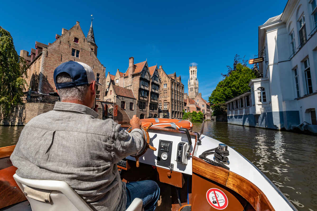 Captain driving a boat around the canals in Bruges - What-to-Expect-on-a-Bruges-Canal-Tour