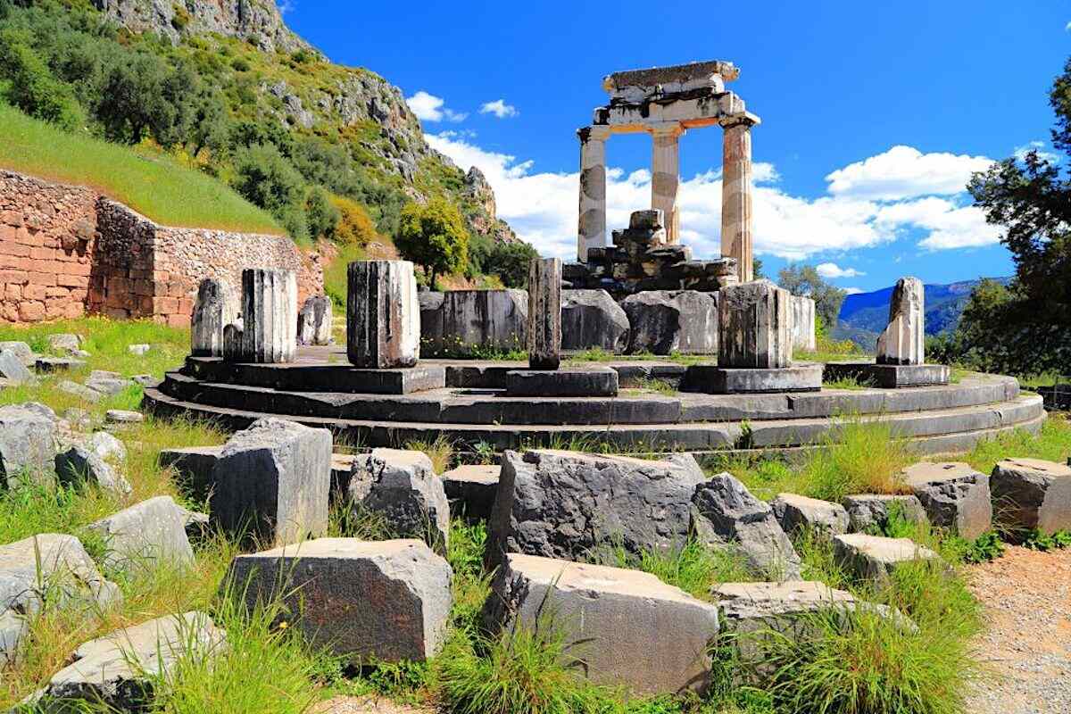 Ruined temple with remaining columns on a hillside. Delphi day tour from Athens