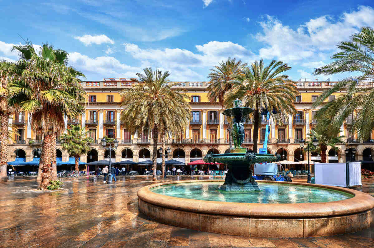 Fountain in a city square with palm trees. Royal area in Barcelona - Plaza Real