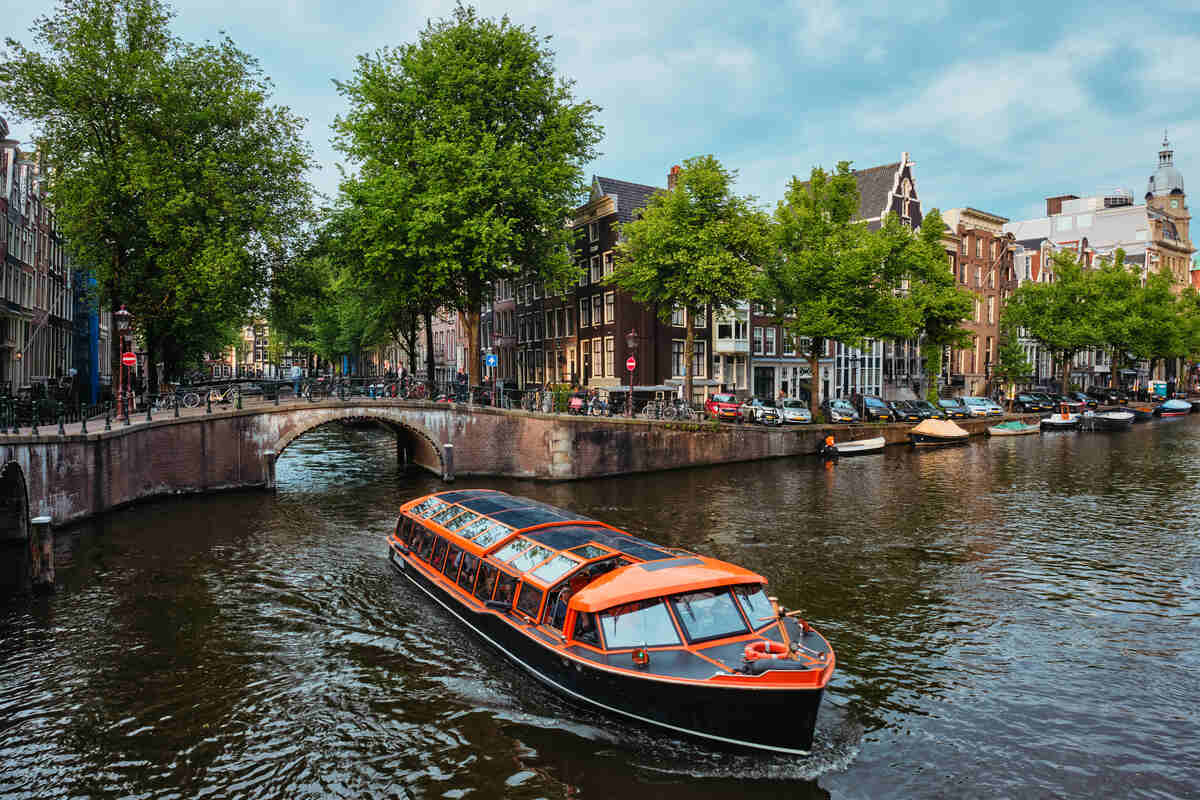 Bridge over a canal with trees and historical buildings.