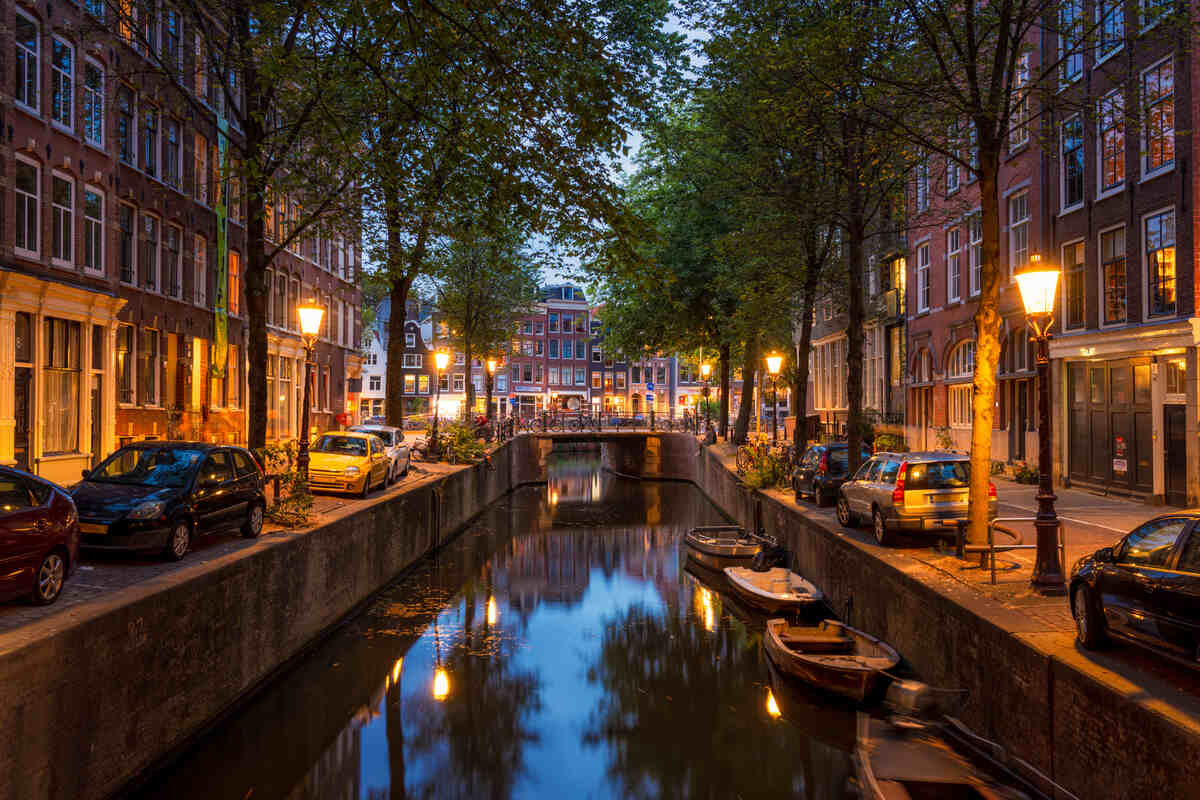 Canal at dusk in Amsterdam with city lights.
