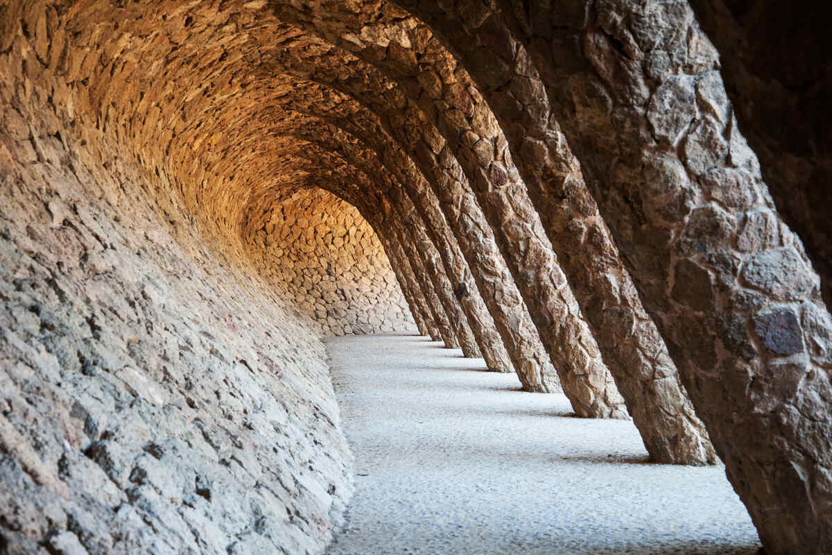 Stone archway in a sunny park Guell in Barcelona.
