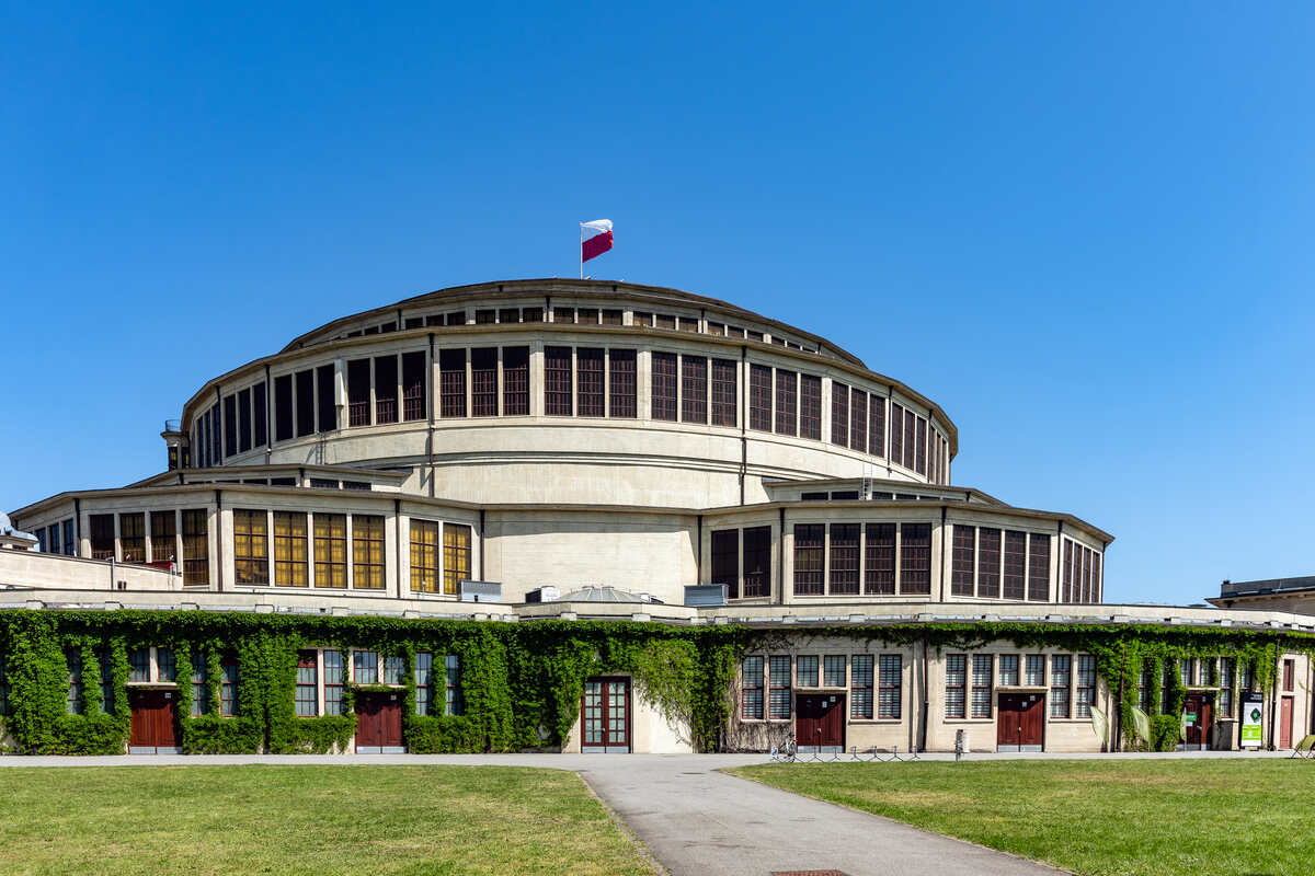 Circular building with flag and clear sky.