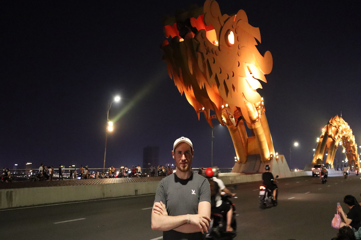 Man posing in front of the dragon bridge at night.