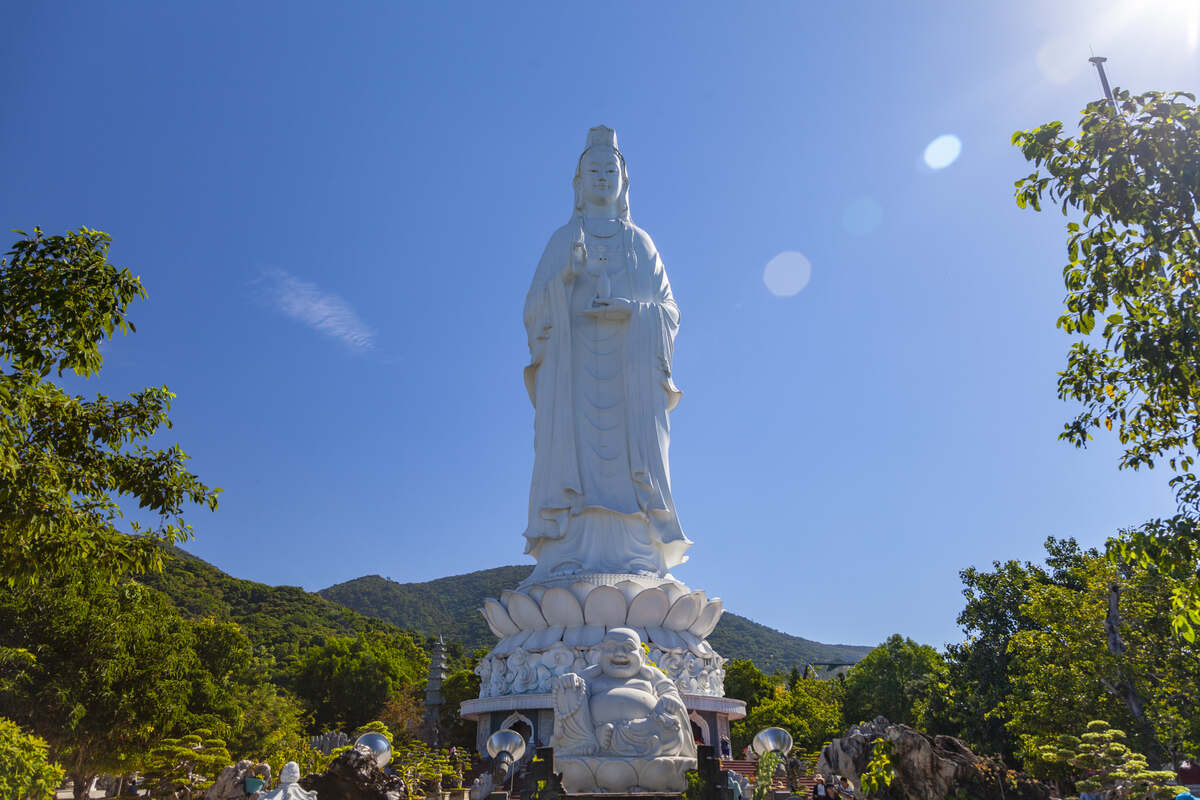 White Buddha statue on a hilltop with clear skies. Lady Buddha Da Nang