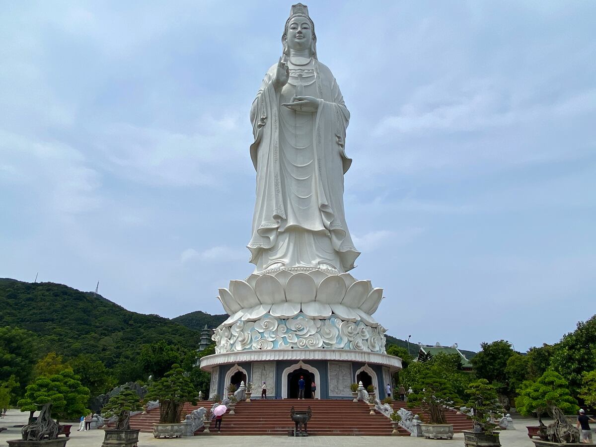 Large white Buddha statue against sky.