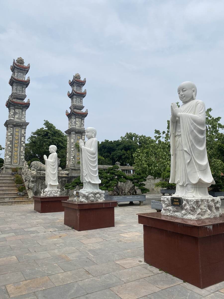 Statues of Buddhist figures on pedestals outdoors.