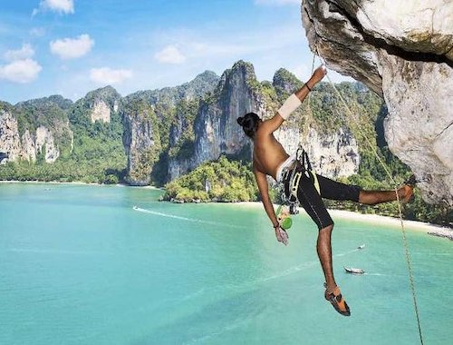 Person rock climbing off a cliff into sea.