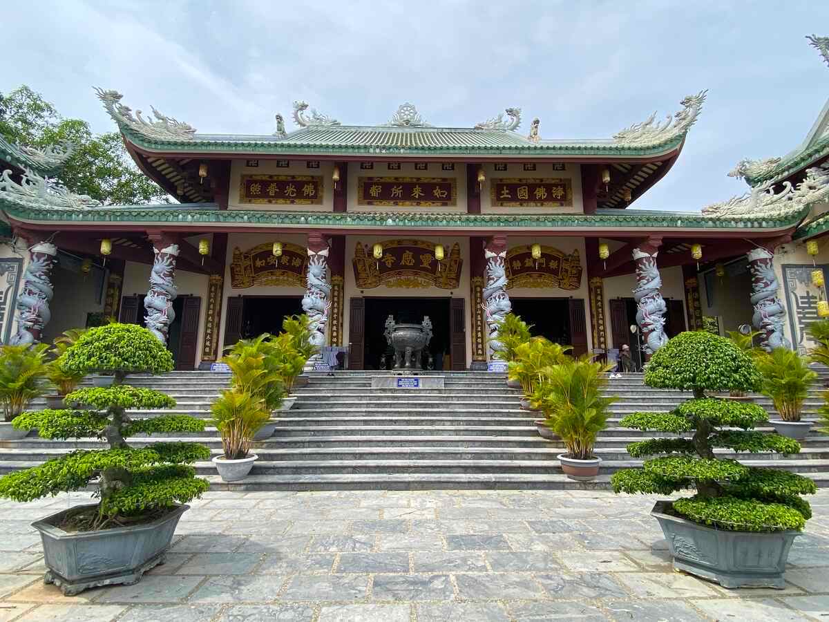 Entrance to a temple with red pillars and a tiled roof.
