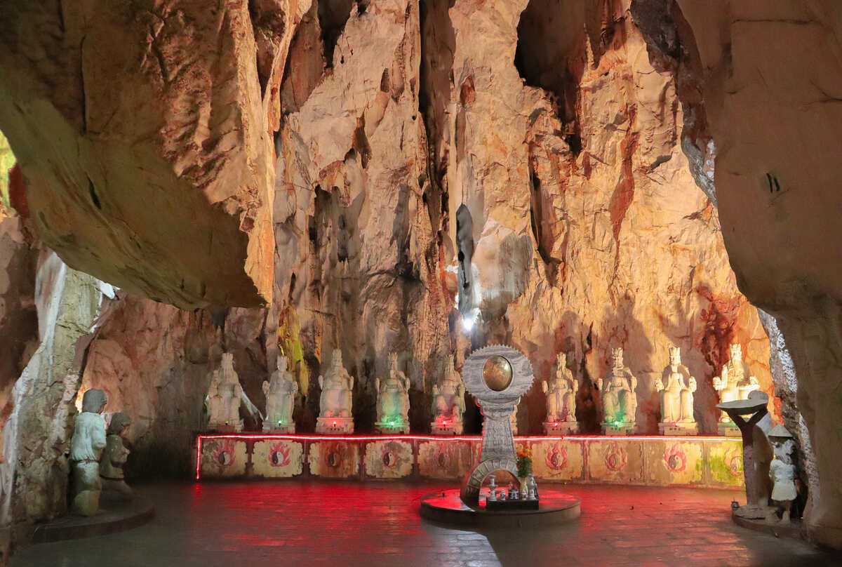 Cave interior illuminated with a red light near a statue.