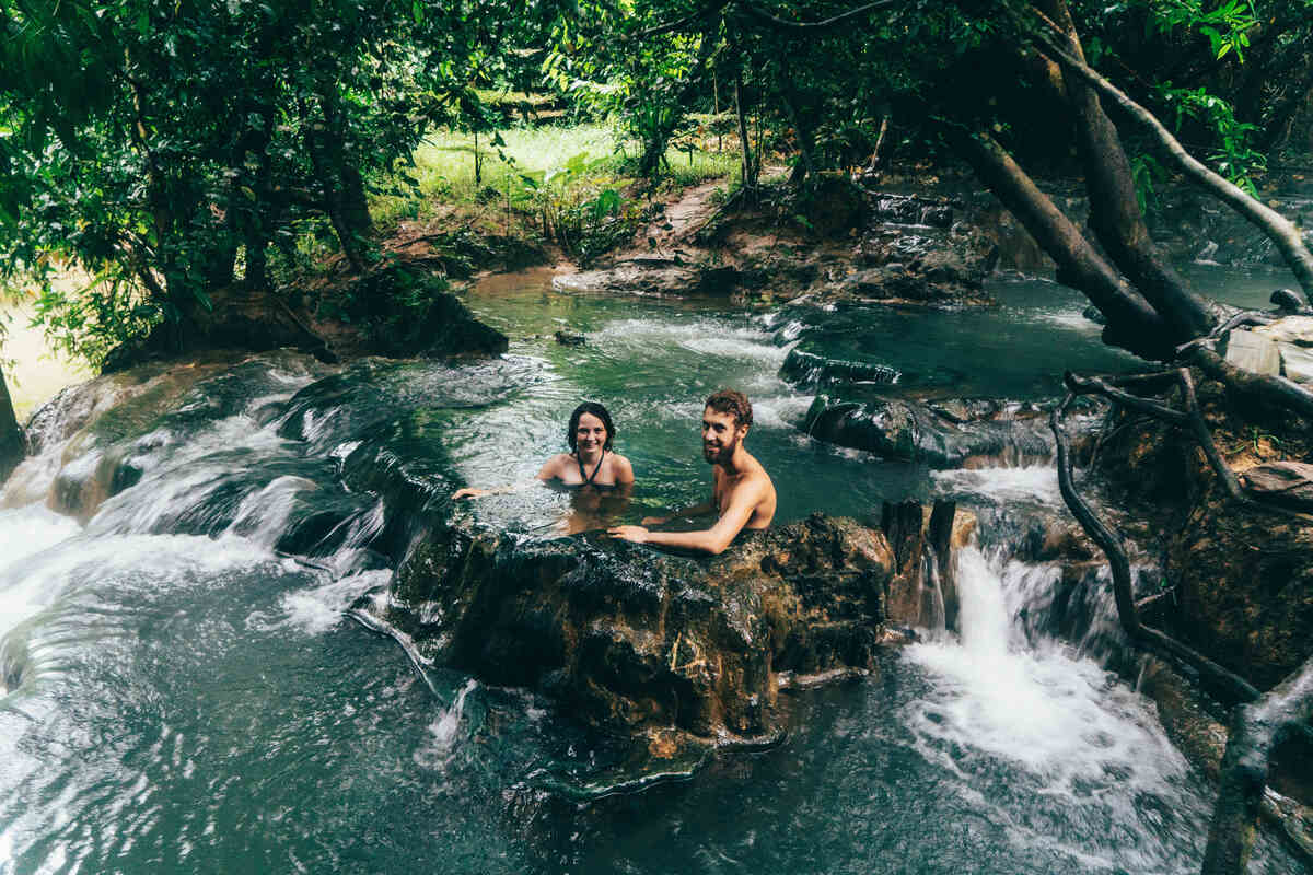 Two people relaxing in a natural pool in the forest.
