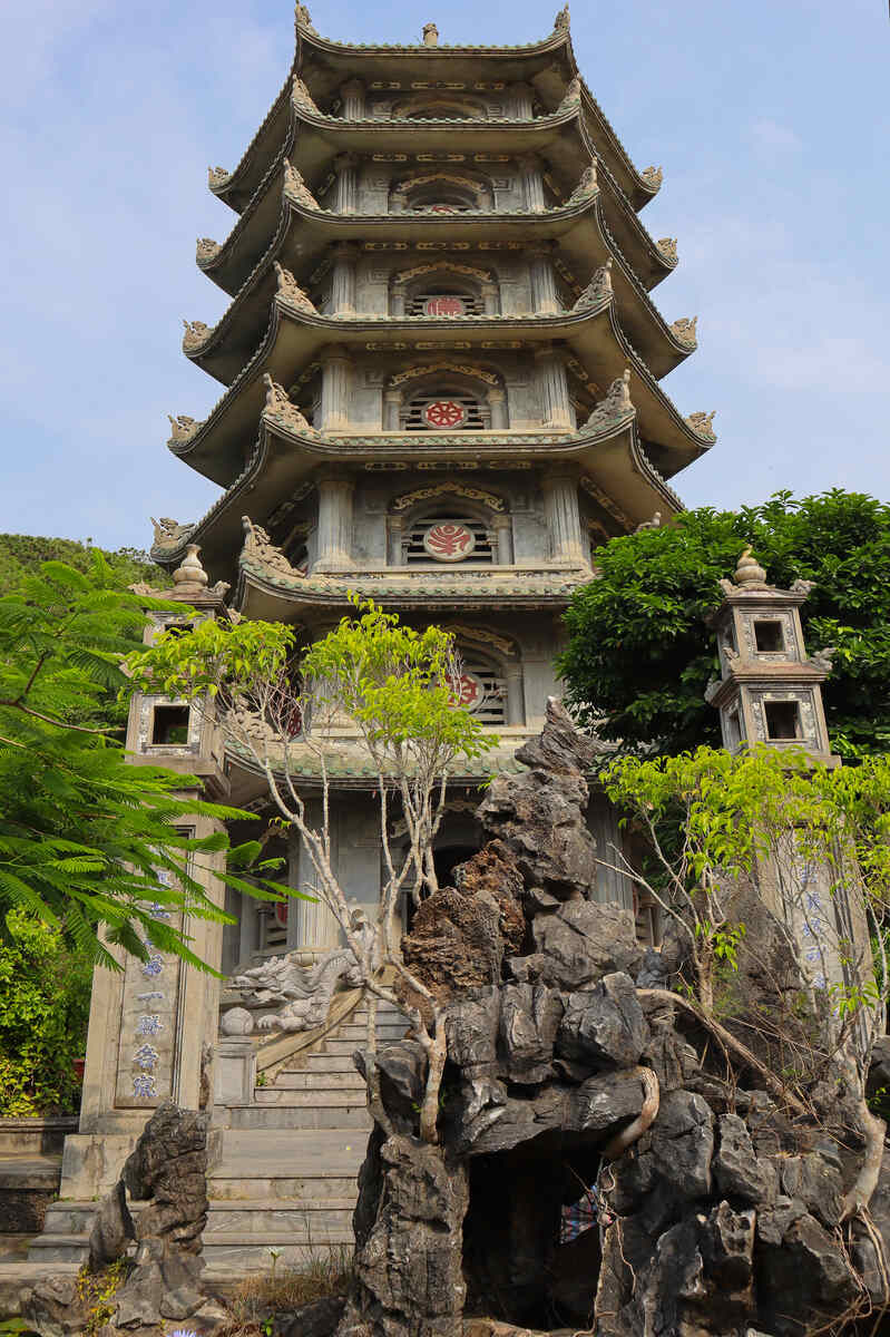 Multi-tiered pagoda on a hillside with greenery.