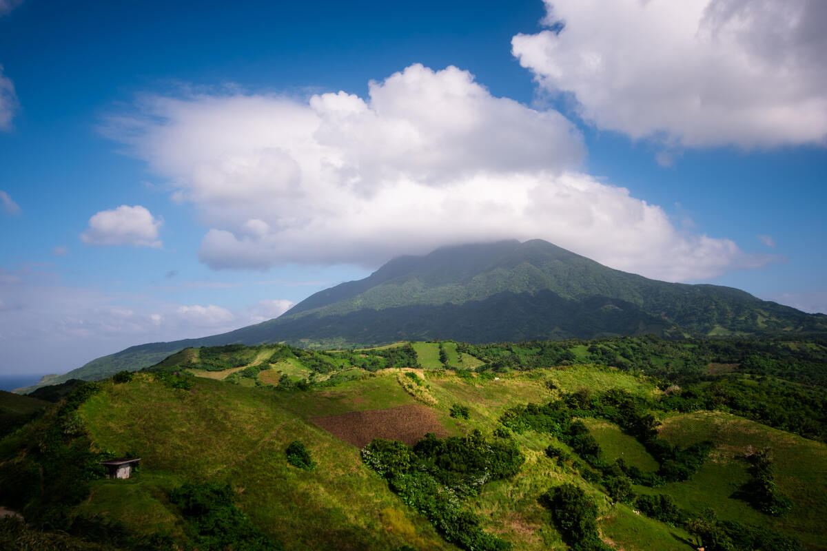 A lush valley with a small village and a mountain in the background. Hike-Mount-Iraya-in-Batanes