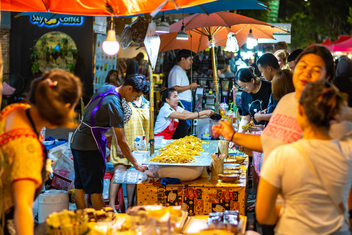 Food stalls with vibrant dishes at an outdoor market.