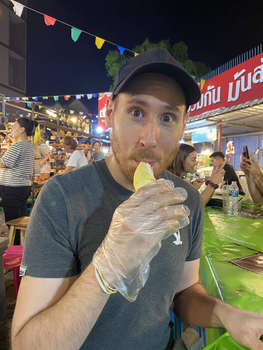 Man eating durian at a market.