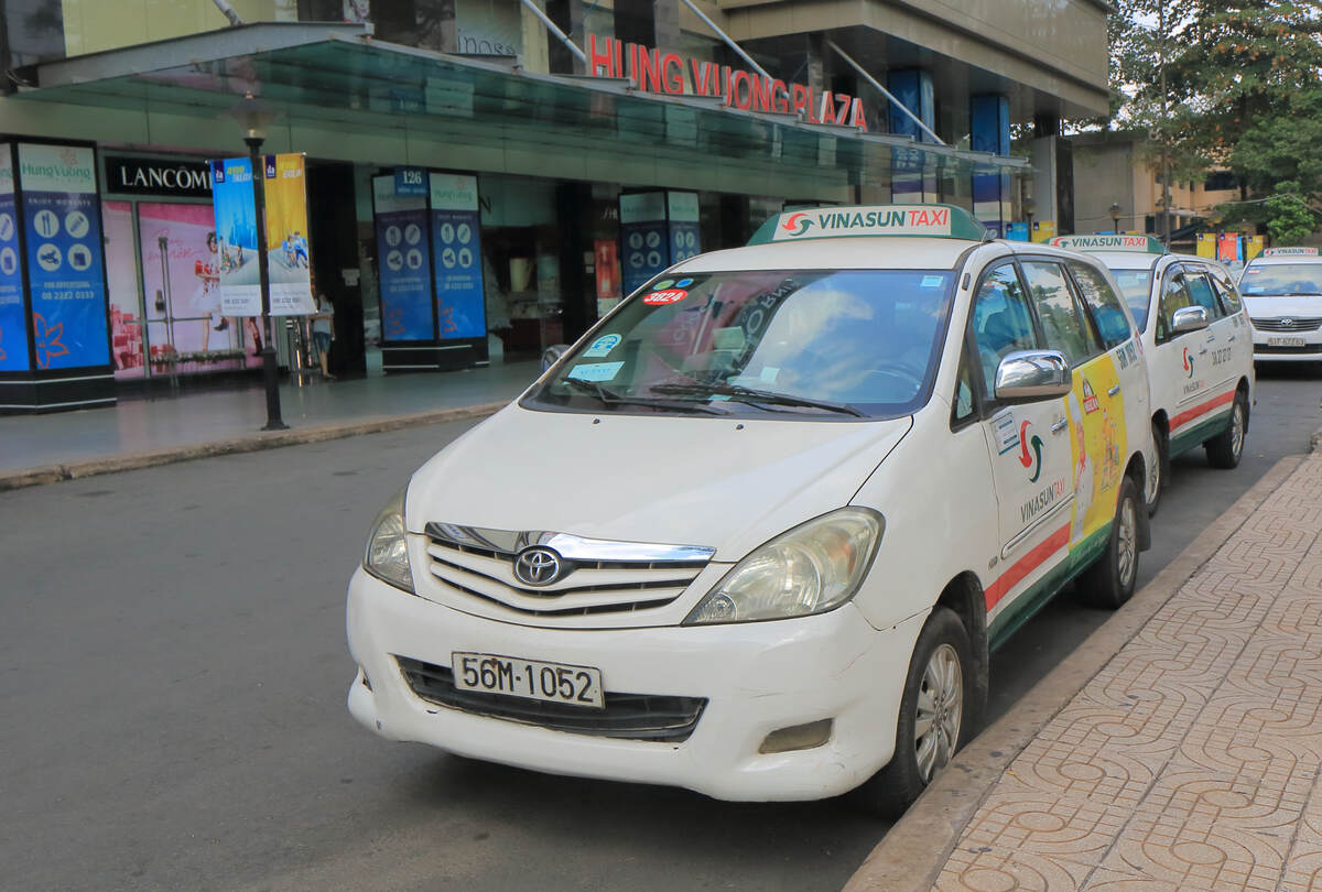 White taxi car parked beside a city walkway. Taxi or Grab Quick and Convenient