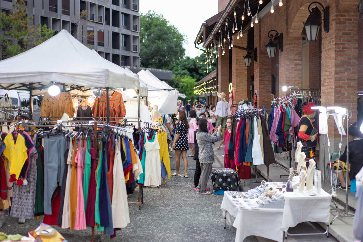 Outdoor market with clothing stalls.