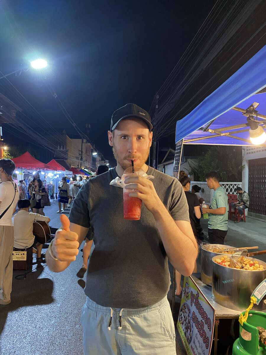 Man drinking a watermelon smoothie at a market.