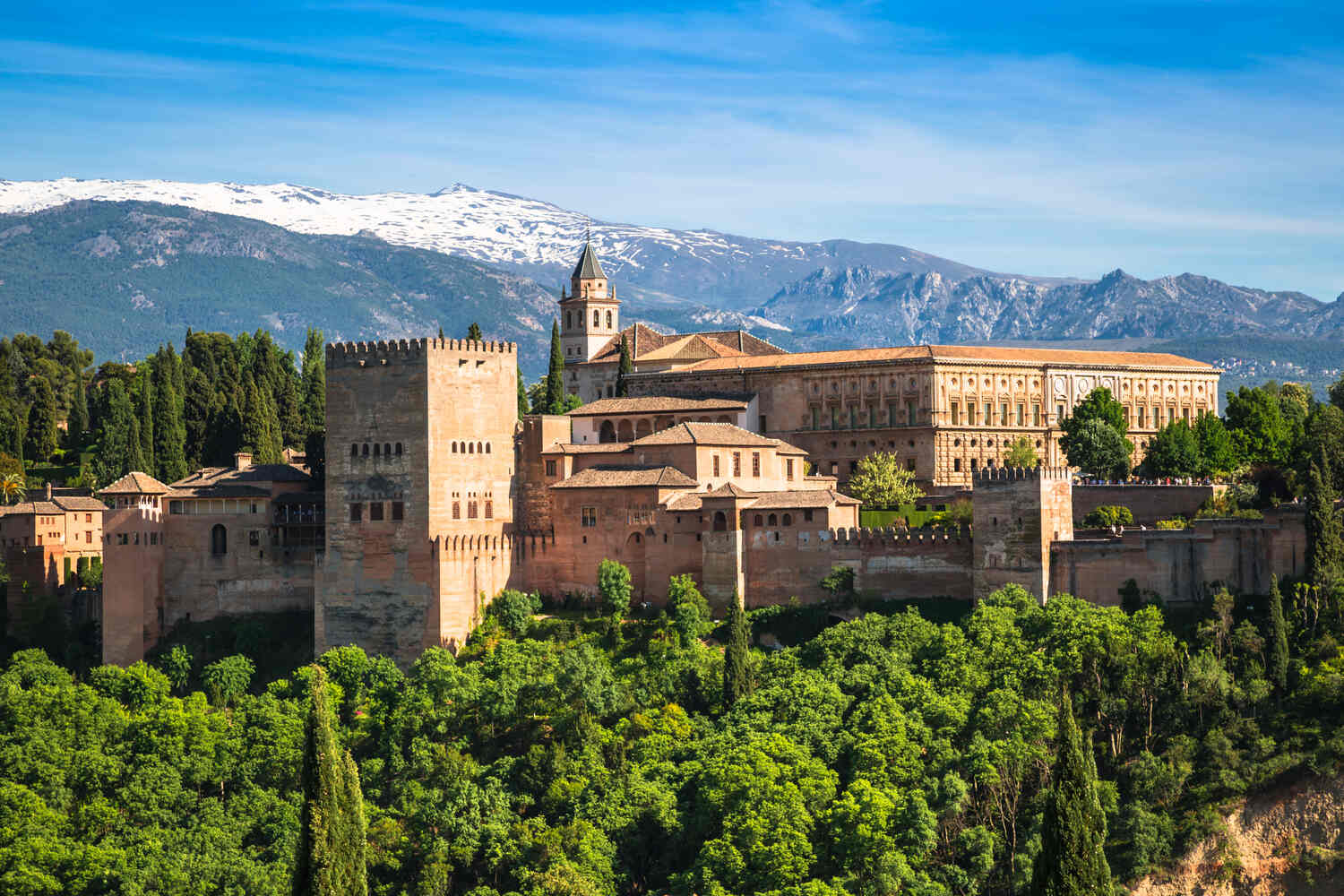 Alhambra on a Seville Day Trip to Granada, Aerial view of Alhambra palace with snow-capped Sierra Nevada mountains behind.