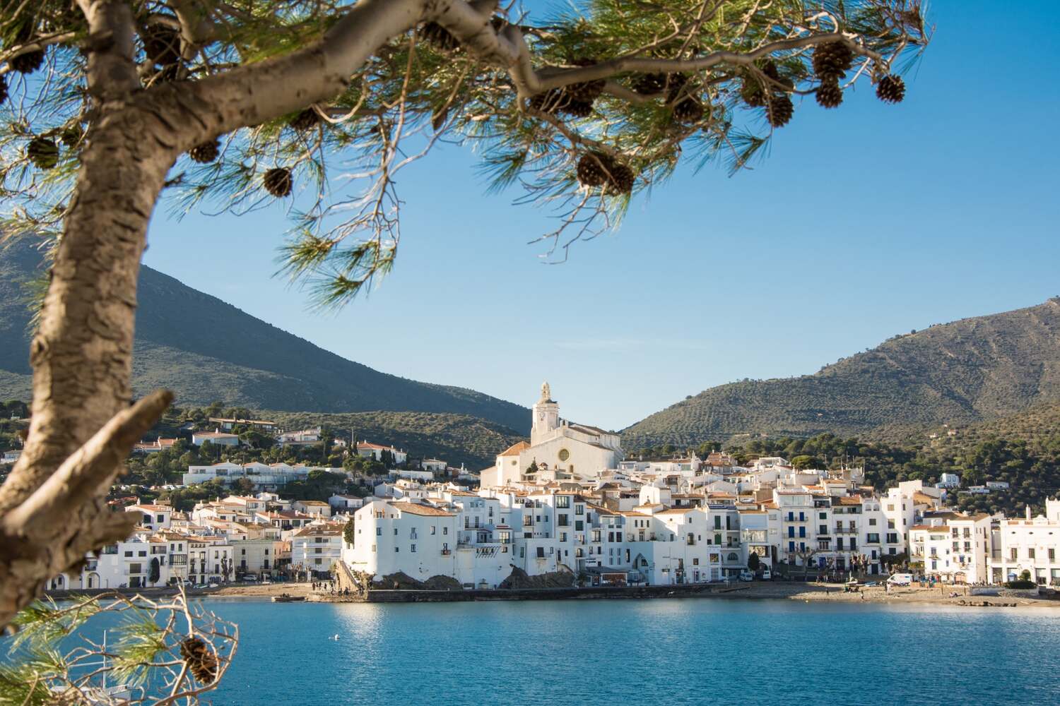 Aerial view of Cadaqués, Spain, showing white houses along the Mediterranean coast.