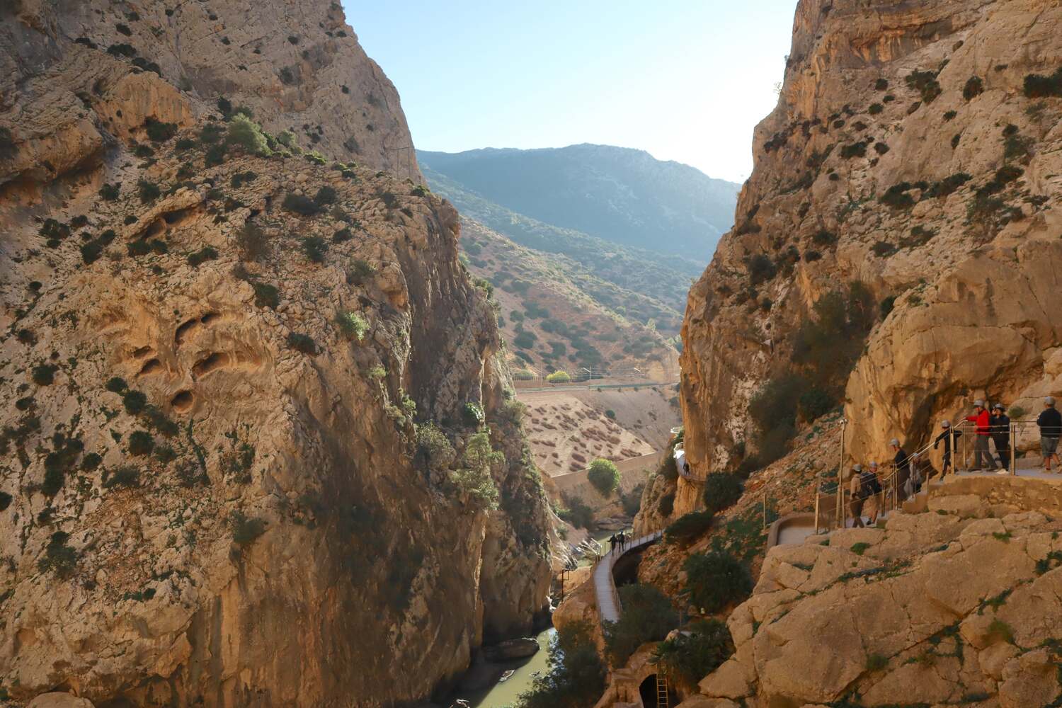 Caminito-Del-Rey-parking, Narrow trail through the rocky gorge of El Caminito del Rey with hikers in the distance.