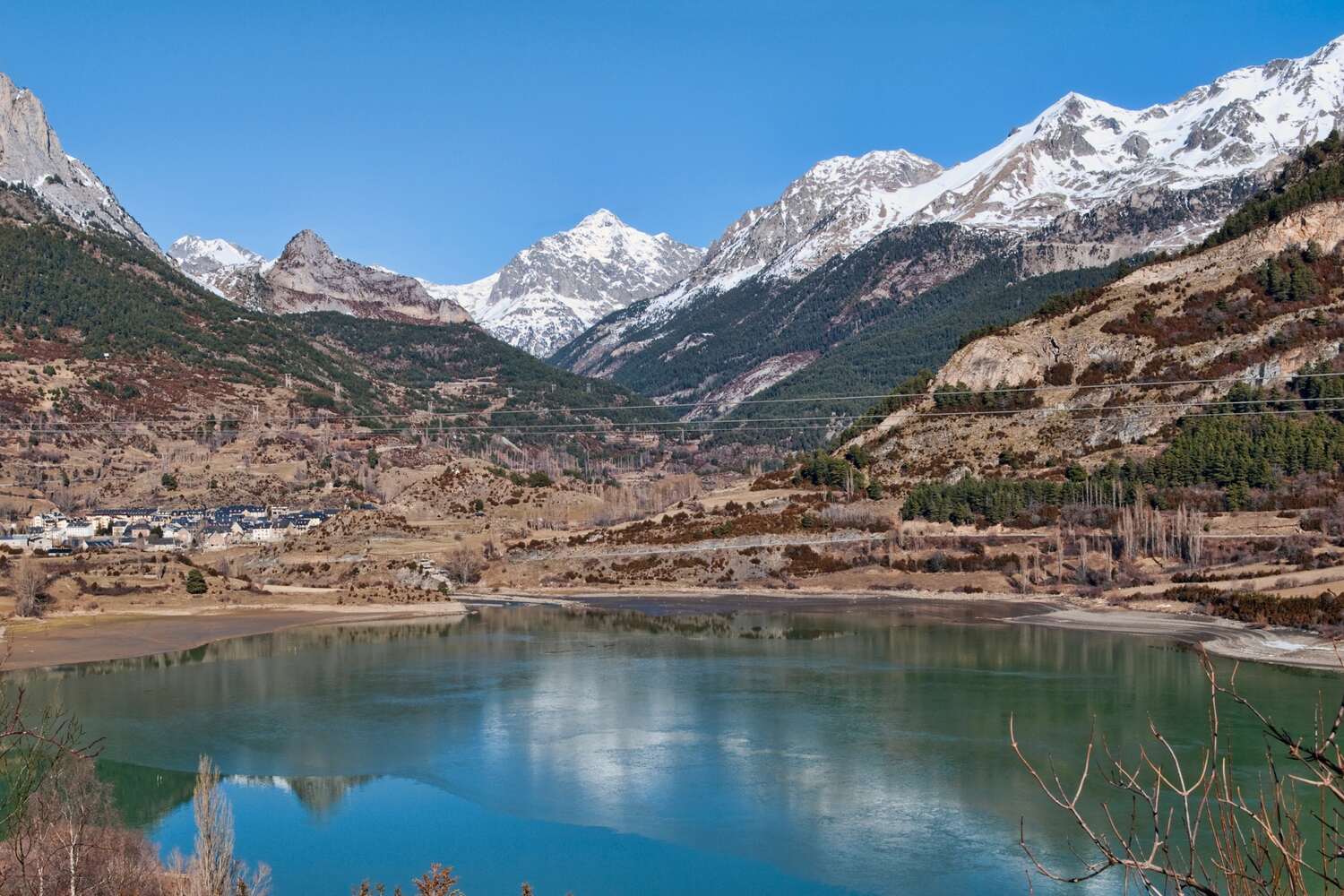 Reflective waters of a reservoir in front of the snow-capped peaks of the Spanish Pyrenees.