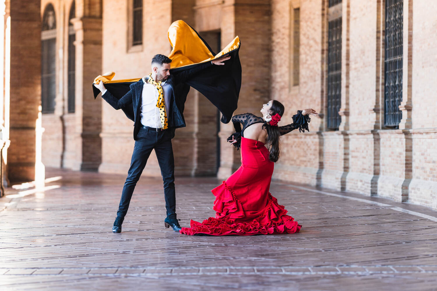 Flamenco dancer in traditional red dress performing in front of a historic building.