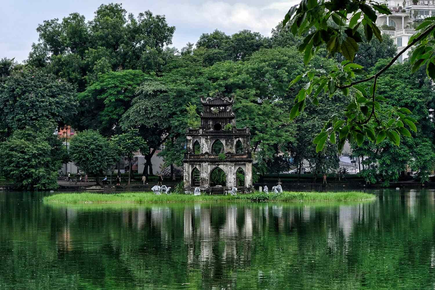 Traditional stone building with a serene pond and lush greenery in Vietnam.