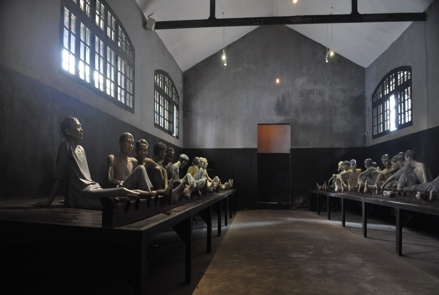 Interior of a museum gallery displaying classical statues of Vietnamese prisonners in a row.