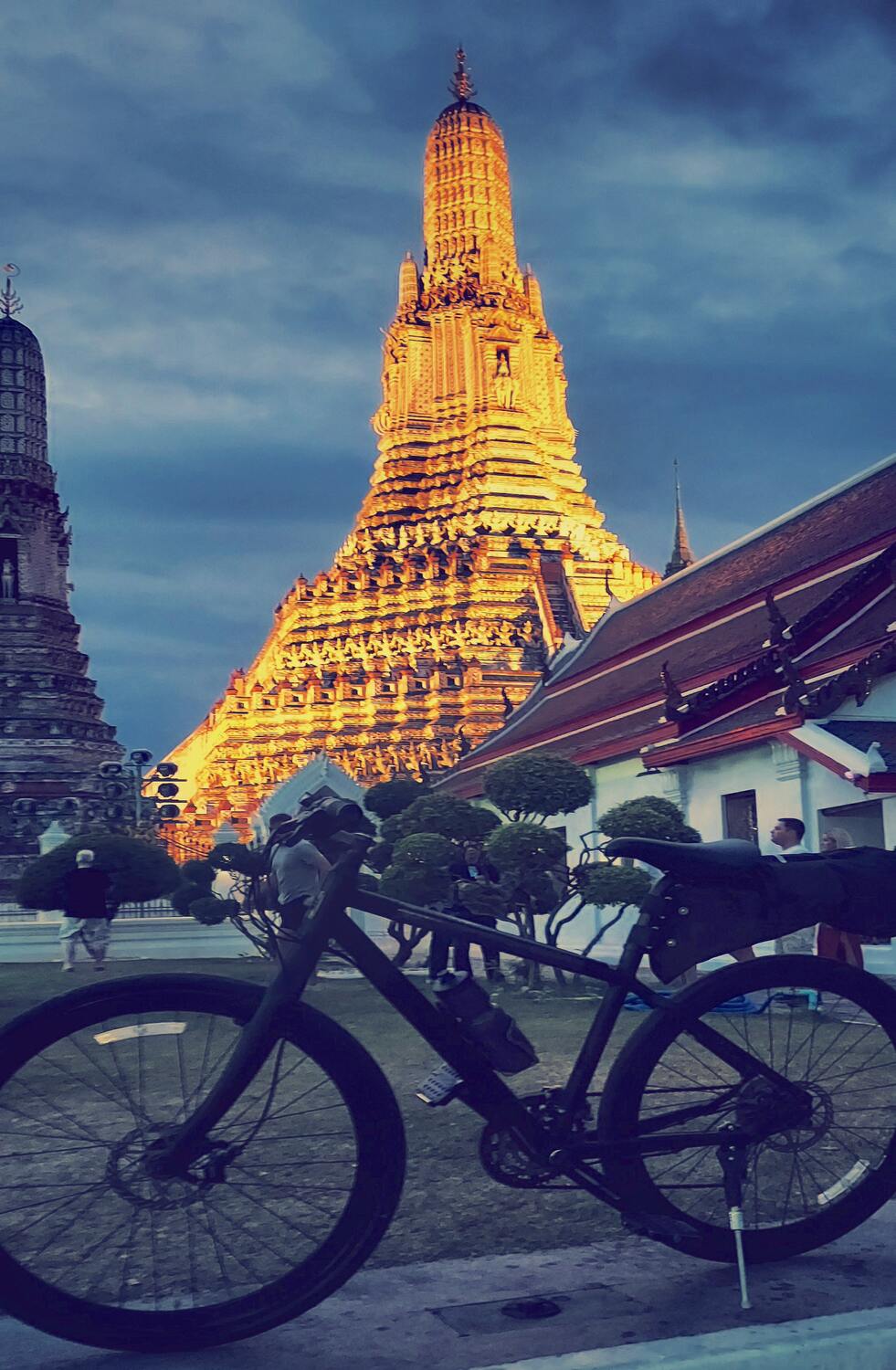 A vintage bicycle parked in front of a temple, with its reflection seen on the wet ground.