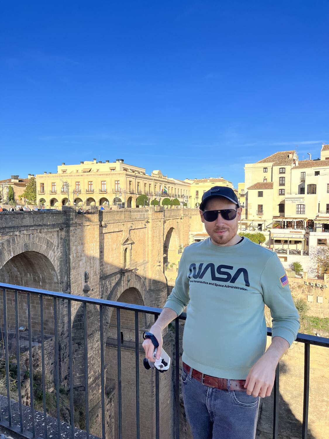 Man posing at a viewpoint in Ronda Spain with the new bridge at the back