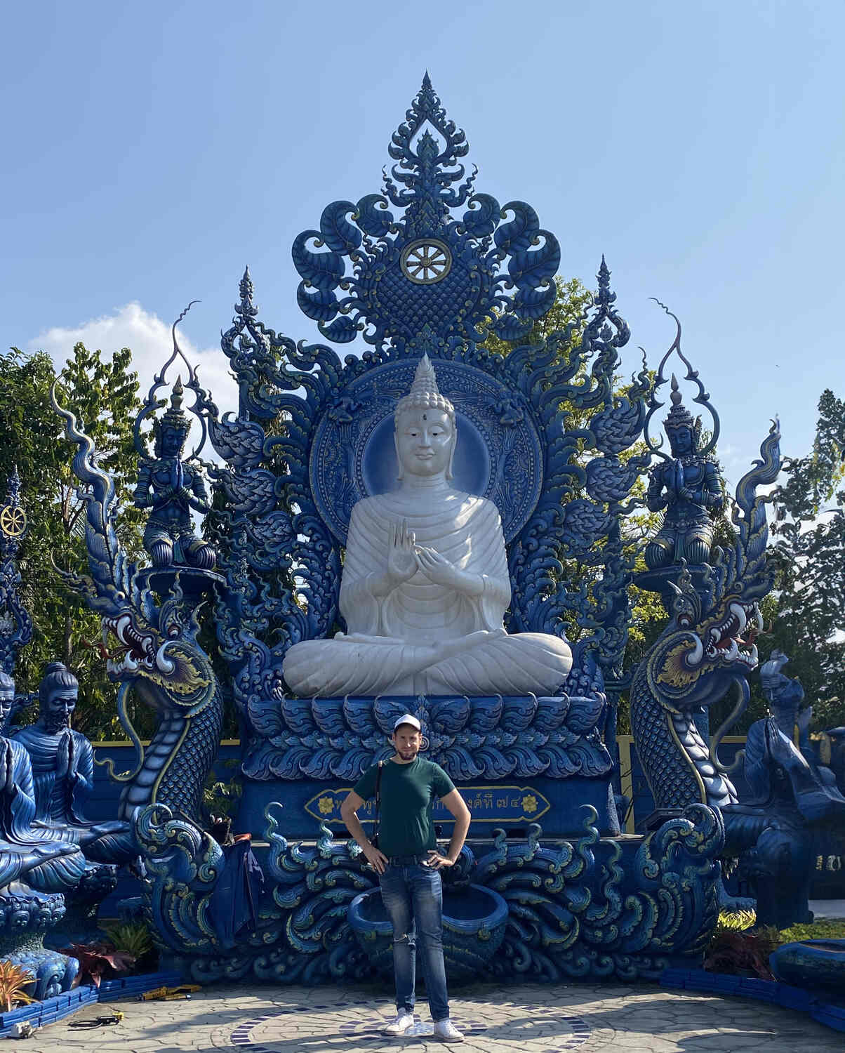 Man posing in front a Buddha image at the blue temple in Chiang Rai
